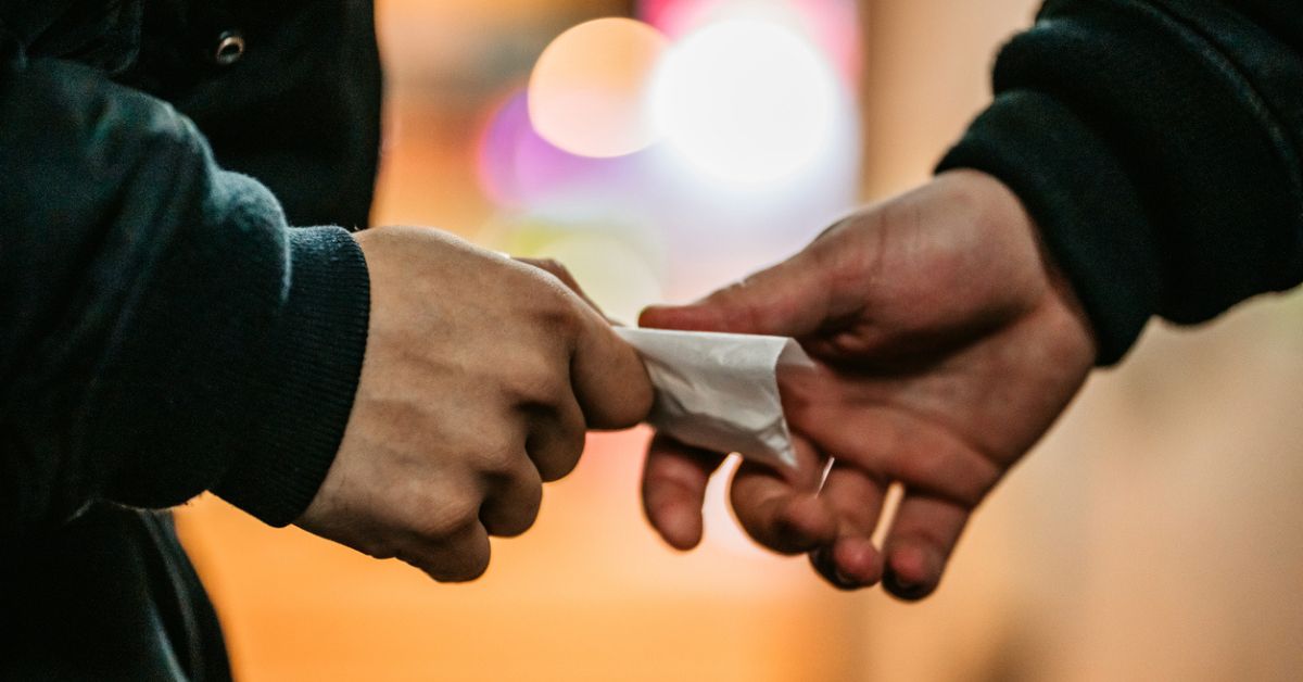 a person handing over drugs to another person